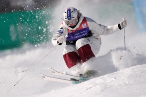 A U.S. skier plunges down a snowfield, knees bent and together, wearing thick snow clothing.