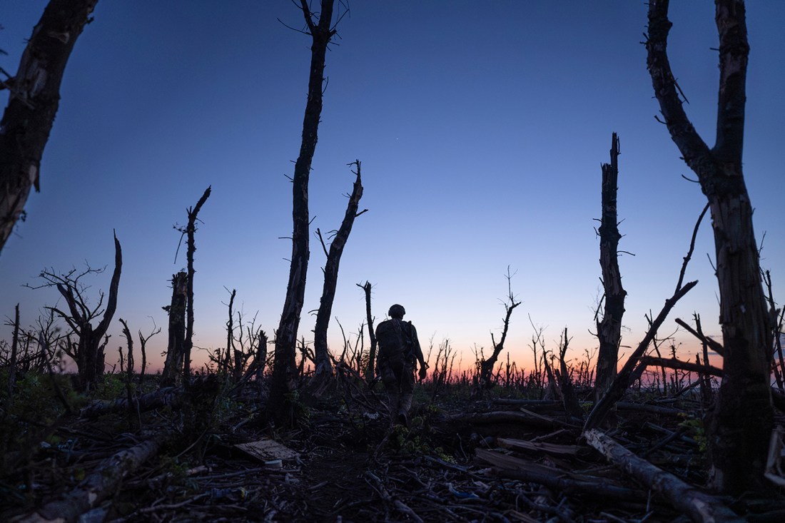 Ukrainian servicemen walk through a charred forest along the front line.