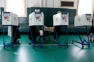 Voters cast their ballots behind confidential booths at an indoor voting station.