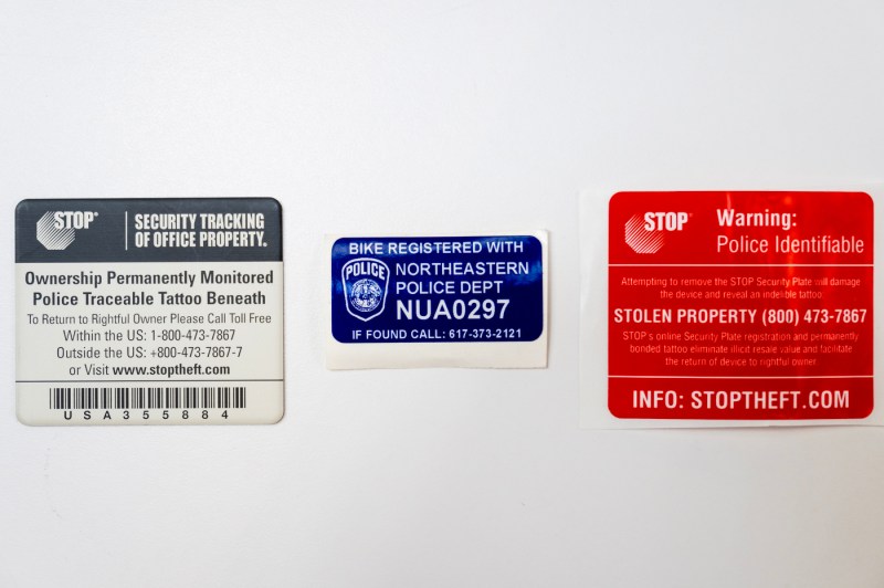 A closeup image of a row of 3 different registration stickers for electronic property and micromobility vehicles like bikes and scooters.