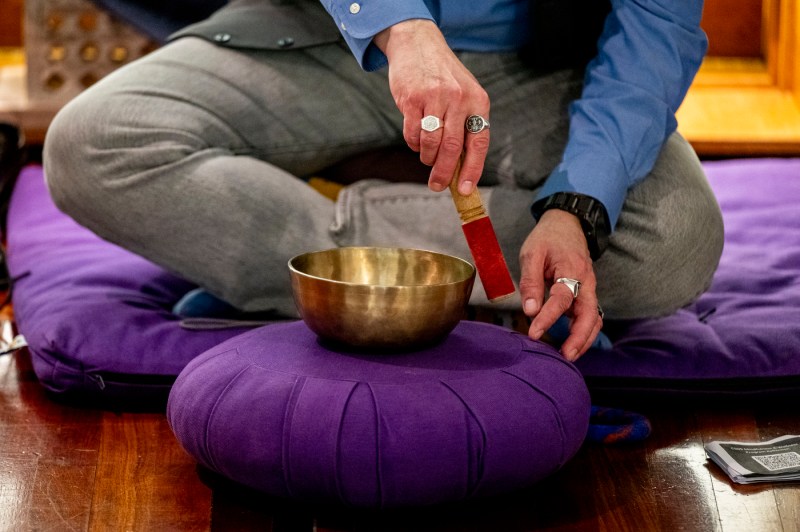 A man uses a sound bowl during a meditation session at Northeastern University.
