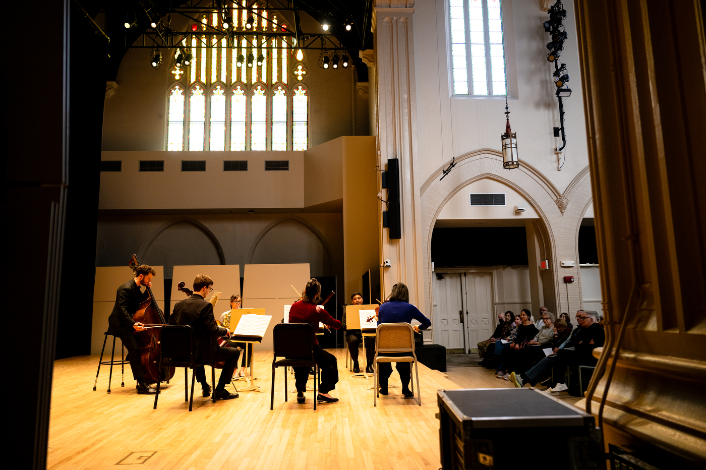 Seven musicians perform for an audience on a stage.