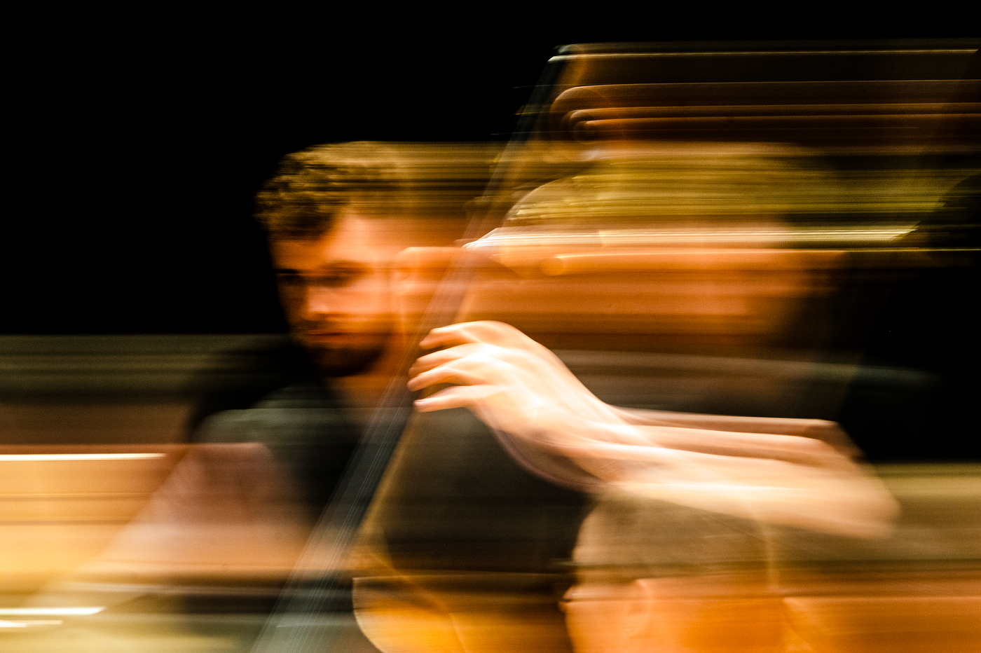 A man plays a large string instrument, the motion of his movements are depicted in panning, which causes lines through the image.