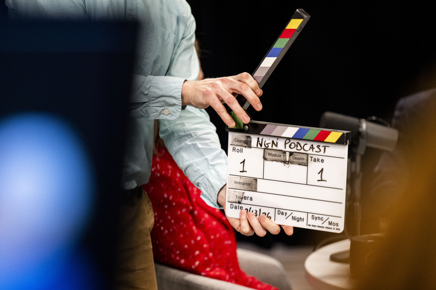 A crew member holds an NGN Podcast clapperboard at the start of filming.