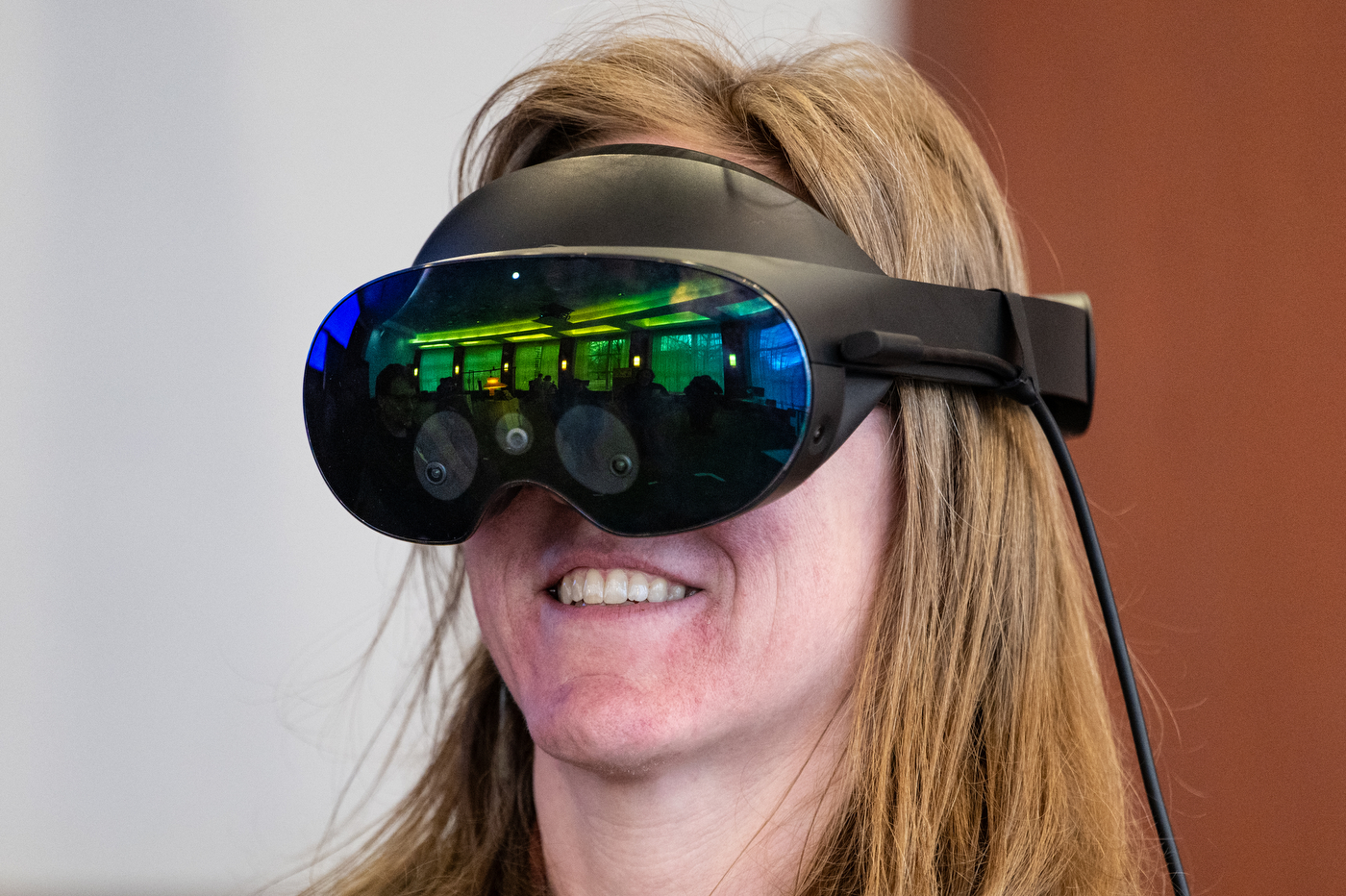 A person wearing a VR headset smiles while testing a new reality art installation. 