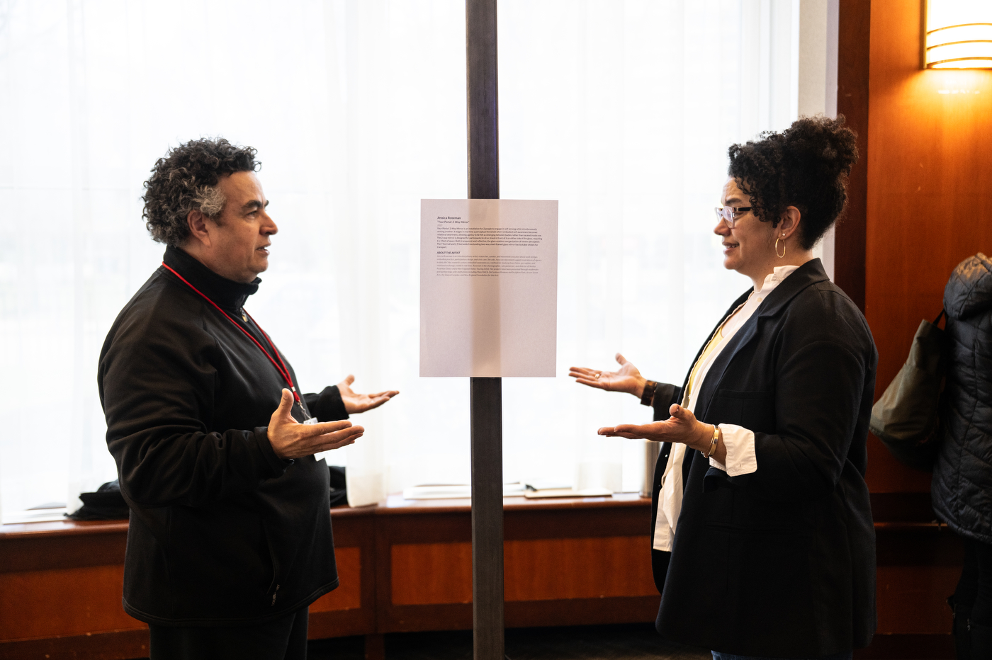 Two people facing each other experiment with interactive art installations.