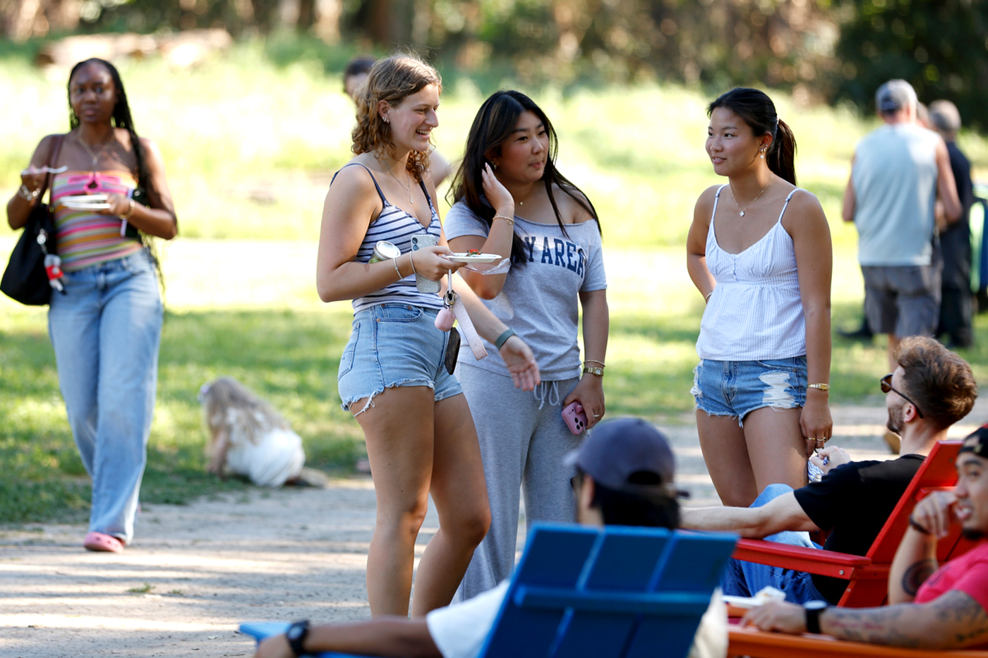 Three women stand together outside next to a dirt path at Farm Fest. 