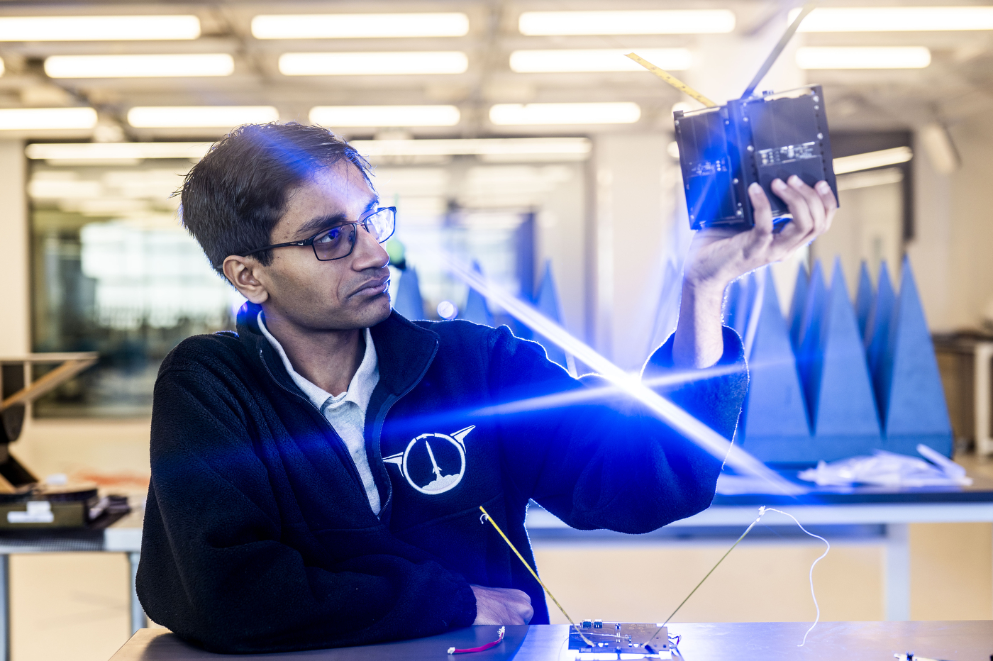 Ganesh Danke holds a protoype of Northeastern's CubeSat satellite in his hands.  