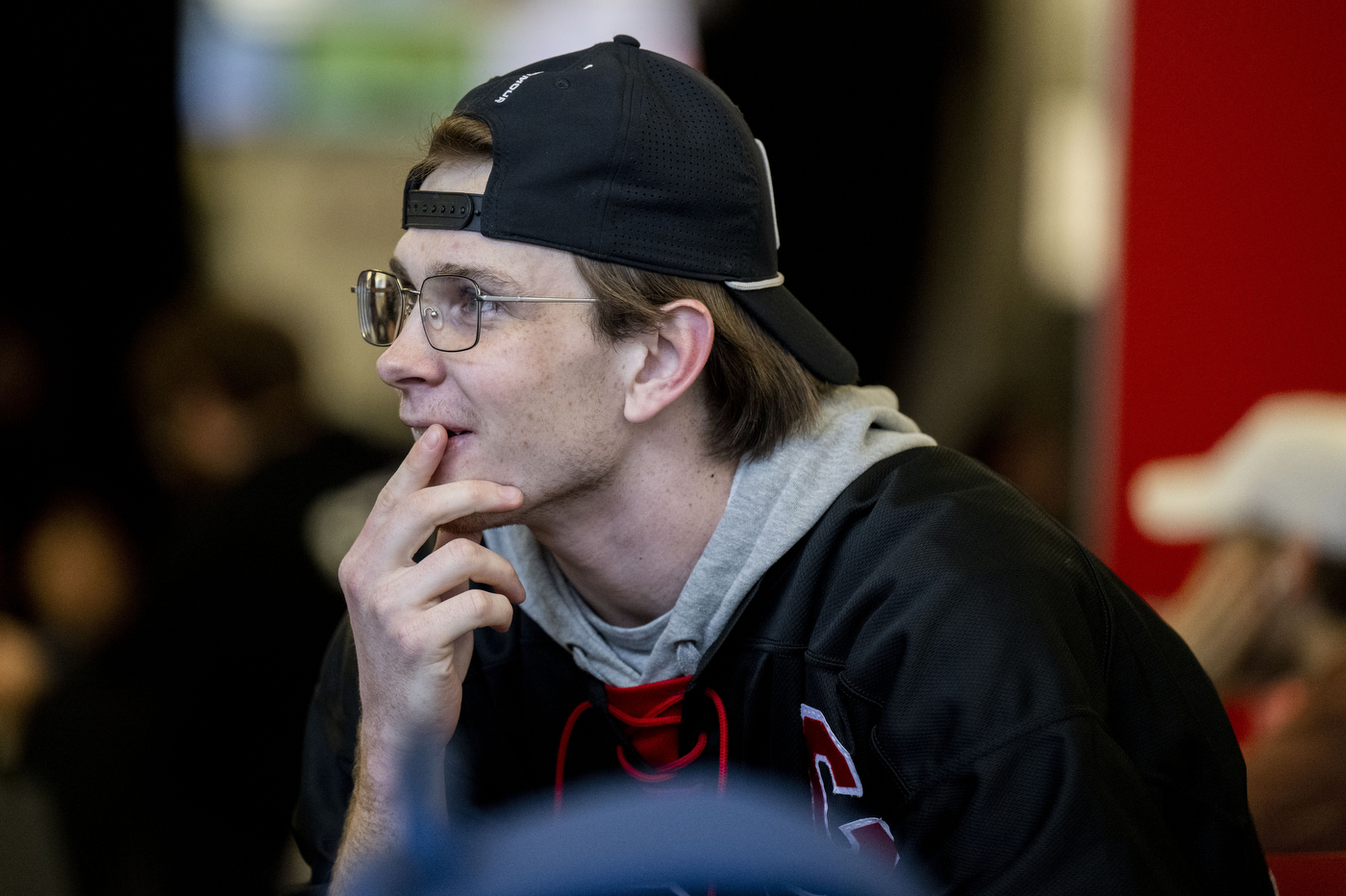 Student watches intently with hand to chin during the Frozen Four semifinal watch party.