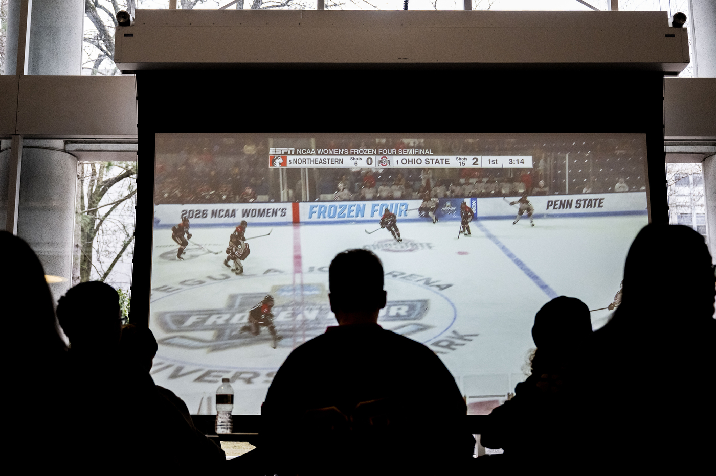 Students watch a broadcast of Northeastern vs. Ohio State on a large screen at Curry Student Center.