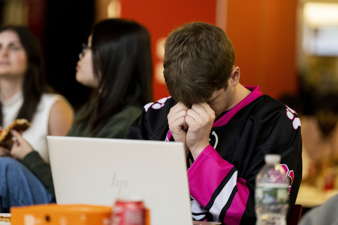 Student bows head while watching Northeastern face Ohio State during a watch party.