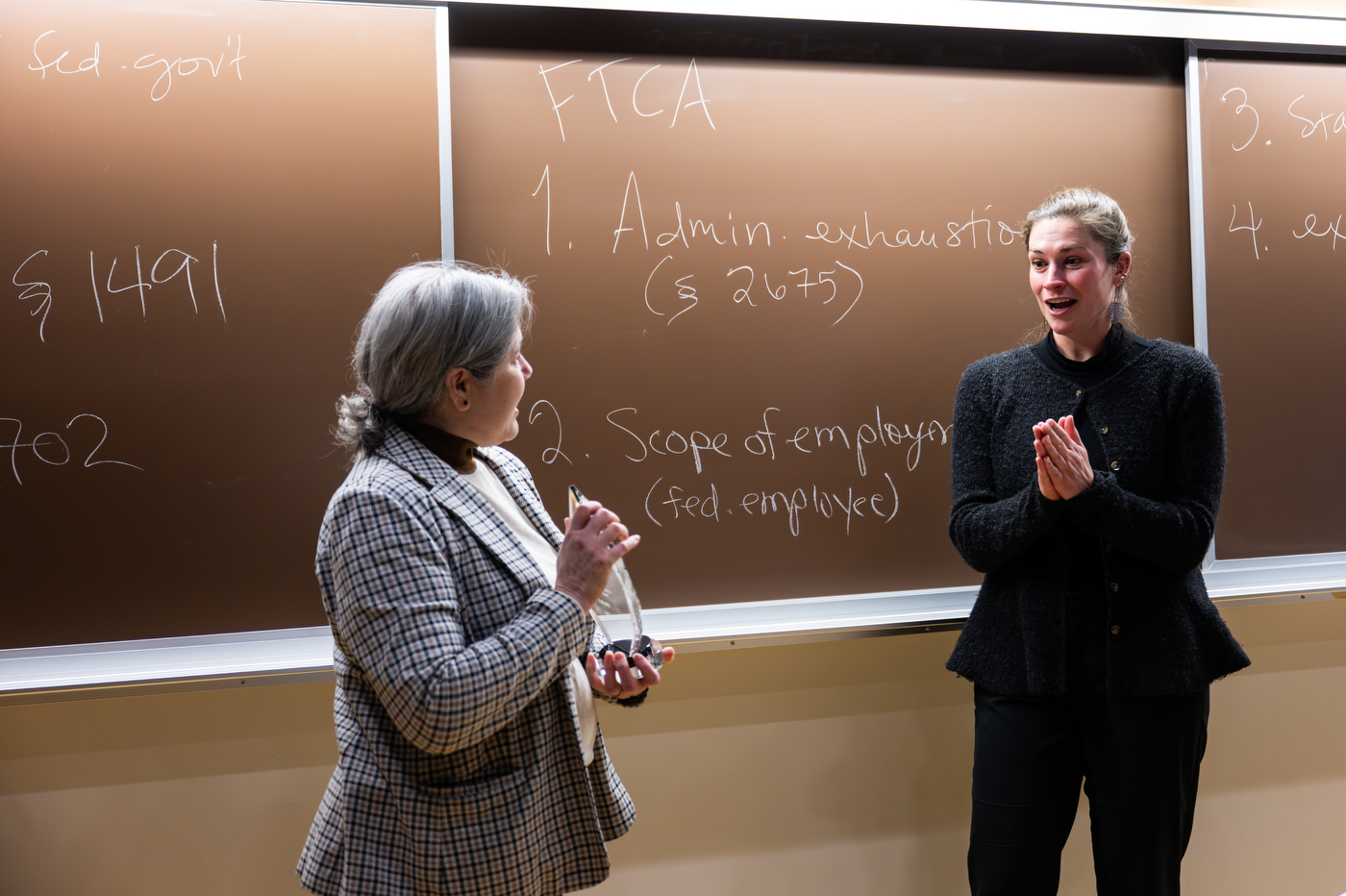Erin Islo, looking shocked, looks at the University Excellence in Teaching Award held by Provost Beth Winkelstein.