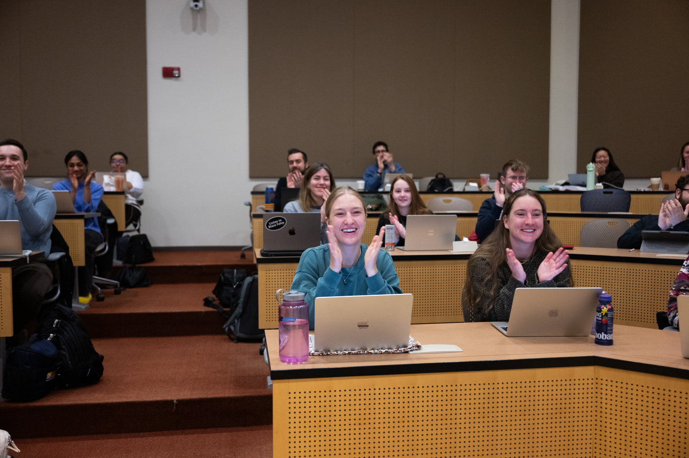 Students look to the front of their classroom while applauding Erin Islo for receiving the University Excellence in Teaching Award.