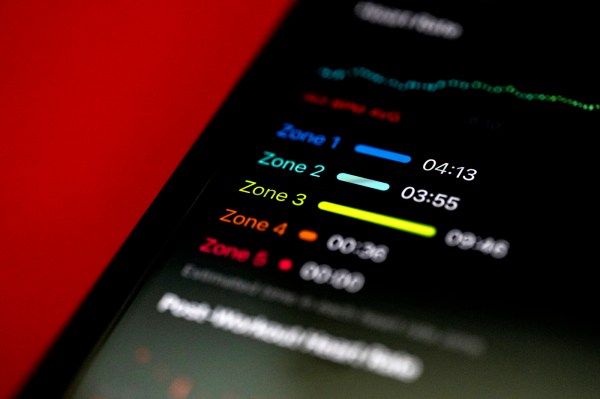 A smartphone displaying information about heart rate zones against a red backdrop.