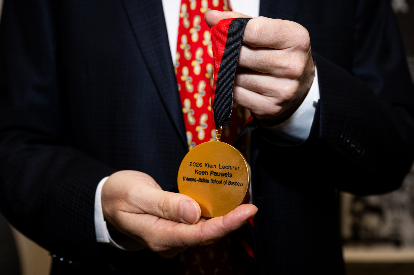 A close-up of a medal. The ribbon on the medal is red and beige. 