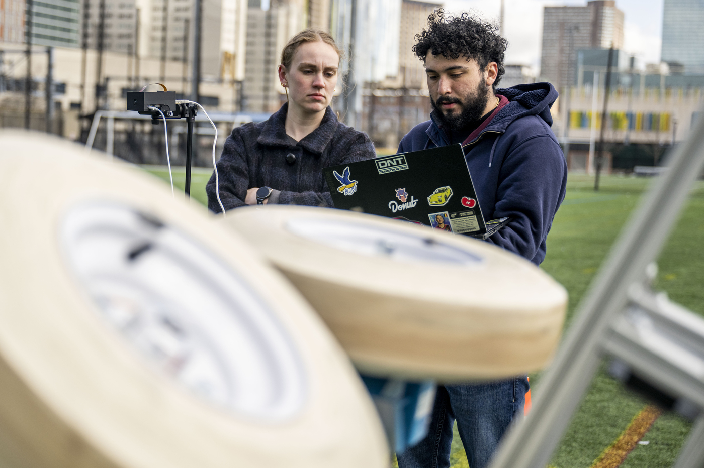 Students work on the equipment of an autonomous football-launching machine. 