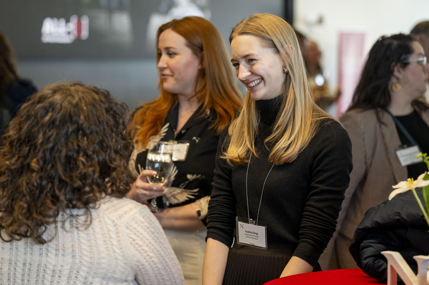 People in a crowd converse and smile at each other.