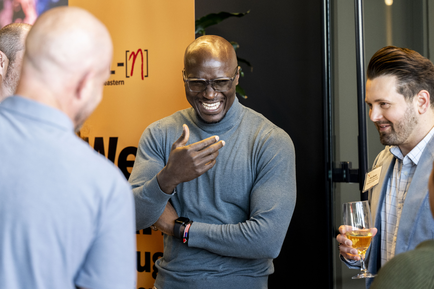 People in a crowd converse and smile at each other.