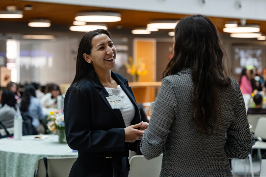 Two women wearing name tags smile and chat during a networking moment at the 2026 WISE Summit on Northeastern’s Boston campus.