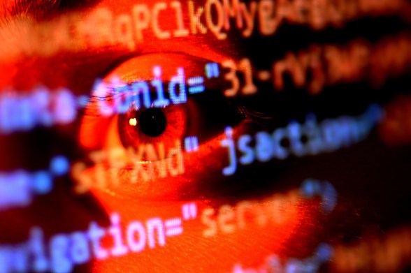 Lines of red and blue code overlaid on a photo of a person's eye lit by red lighting.
