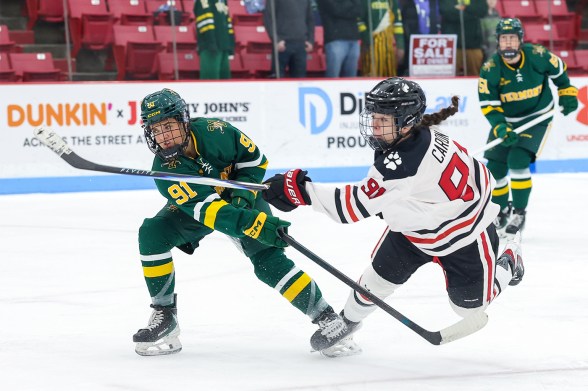 Two women's hockey players face off for a puck.