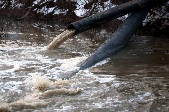 Brown sewage water coming out of pipes into the Potomac River.