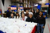 Students from Agents of Social Impact pose together in a warehouse while volunteering at a local nonprofit.