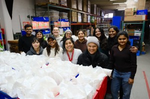 Students from Agents of Social Impact pose together in a warehouse while volunteering at a local nonprofit.