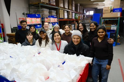 Students from Agents of Social Impact pose together in a warehouse while volunteering at a local nonprofit.