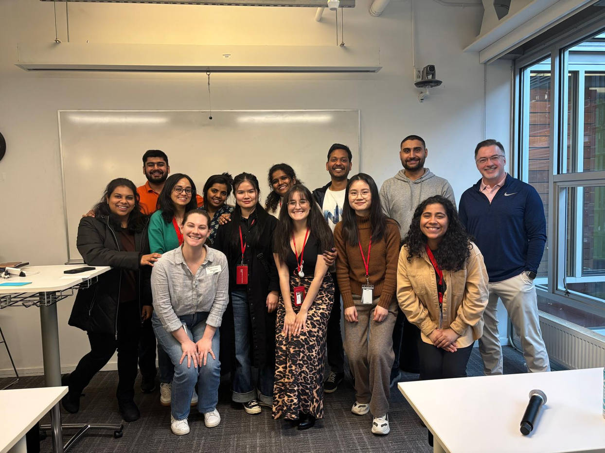 Students and faculty gather in a classroom and pose for a group photo.