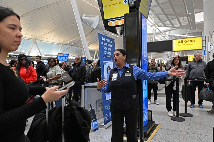 A TSA agent directing travelers in the airport lobby.