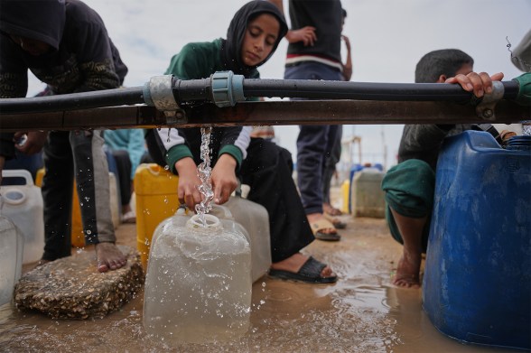 A person filling a plastic jug of water at a desalination plant.