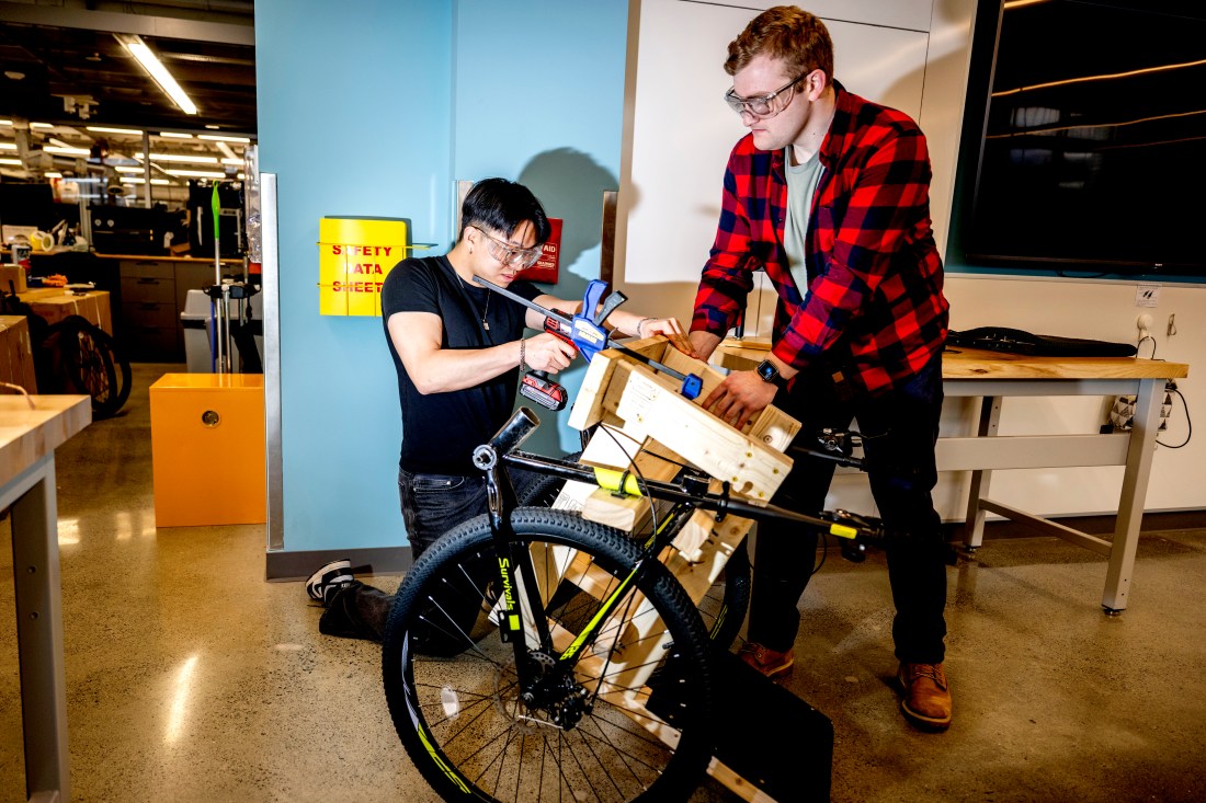 Bioengineering students Chris Shih and Michael Cerny assemble a wooden wheelchair frame with bicycle wheels. 
