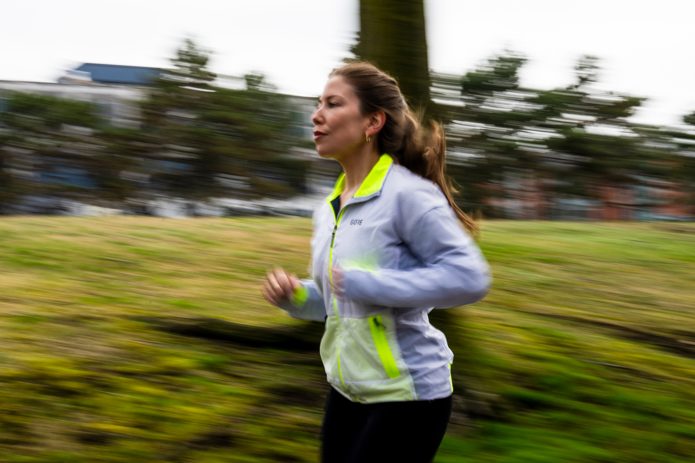 Megan Doe runs outside against a background of blurred grass and trees