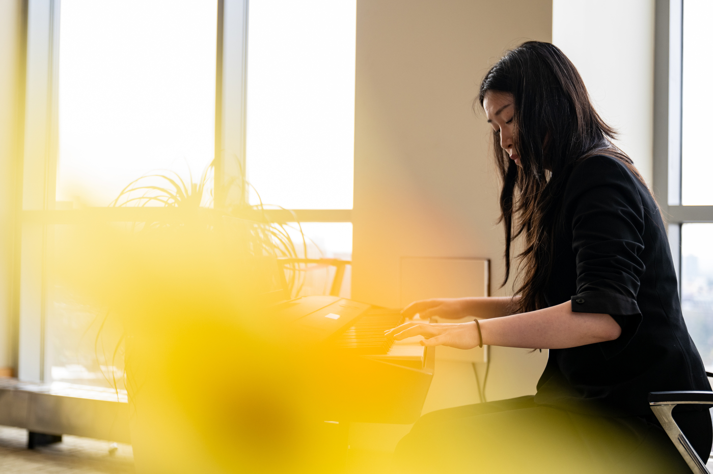 A student performs at a keyboard instrument during the spring 2026 Huntington 100 induction ceremony, bathed in warm golden light.