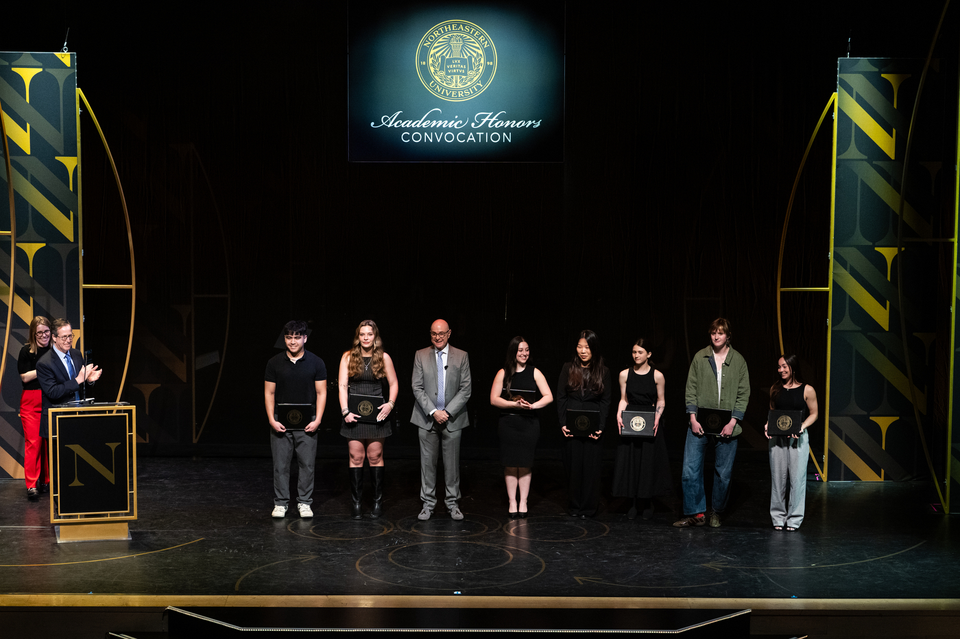 President Aoun posing on stage with a group of students and faculty. 