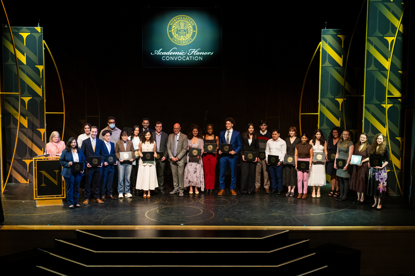 President Aoun poses on stage with a large group of people at the Academic Honors Convocation.