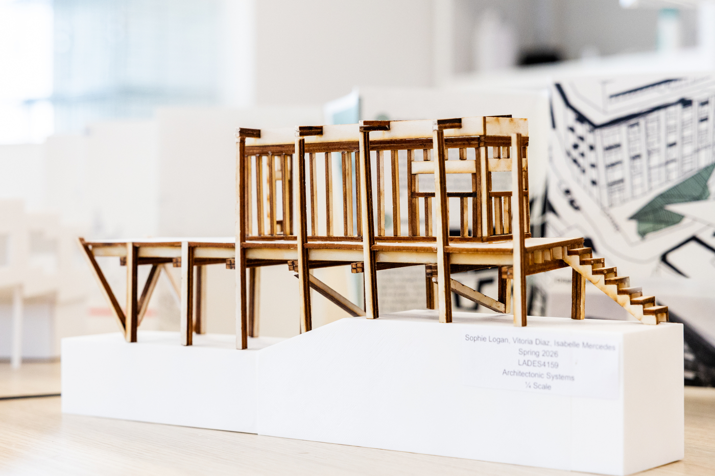 A wooden 3D architectural model stands on a white playform