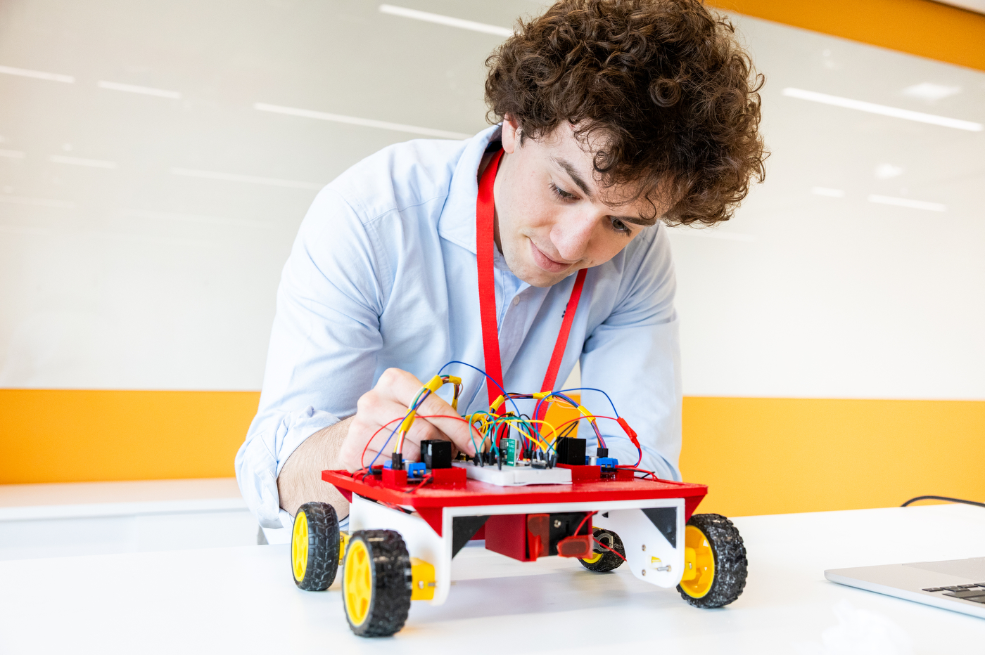 A Northeastern London student bends over a robot on wheels