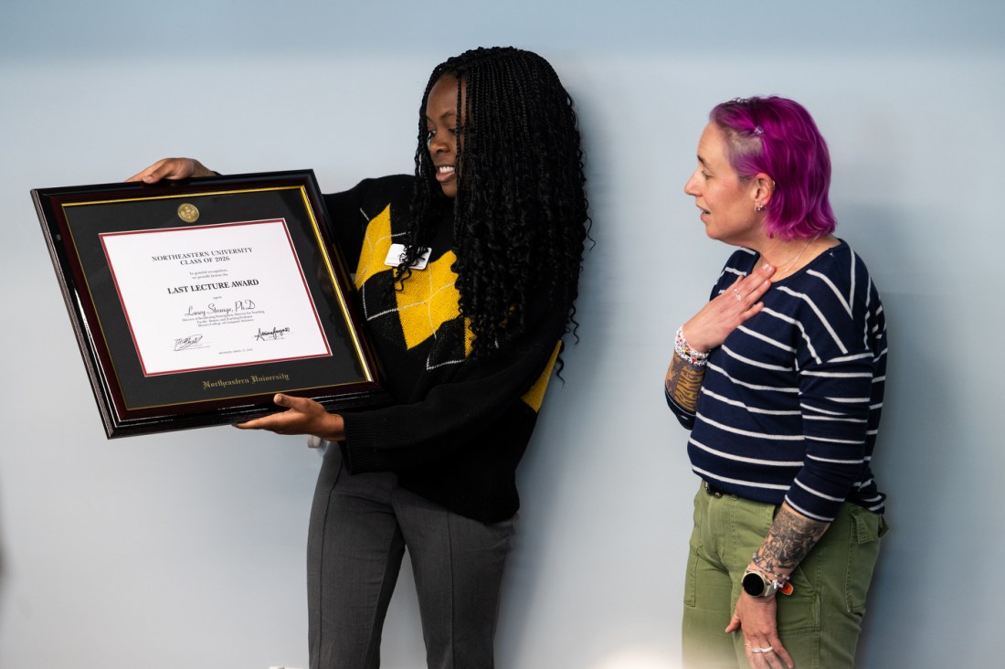 A student presents Laney Strange with a framed certificate at Northeastern's Last Lecture 2026.