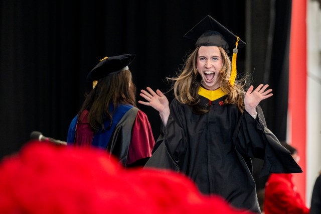 A graduate celebrates as she walks across the stage.