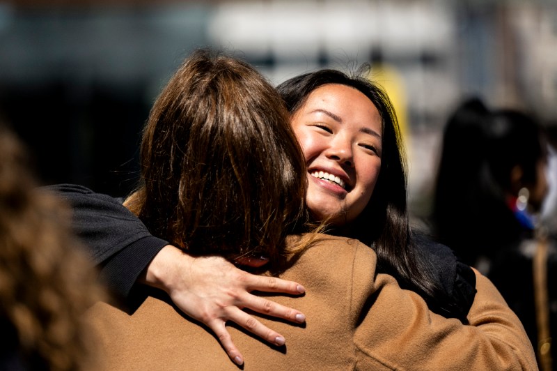 A graduate shares a warm embrace with another person.