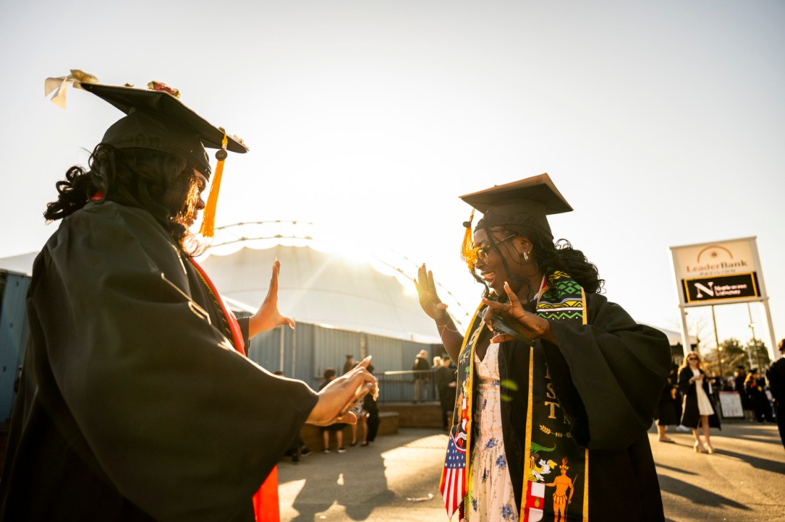 A low angle shot of two graduates in their caps and gowns dancing an celebrating together.