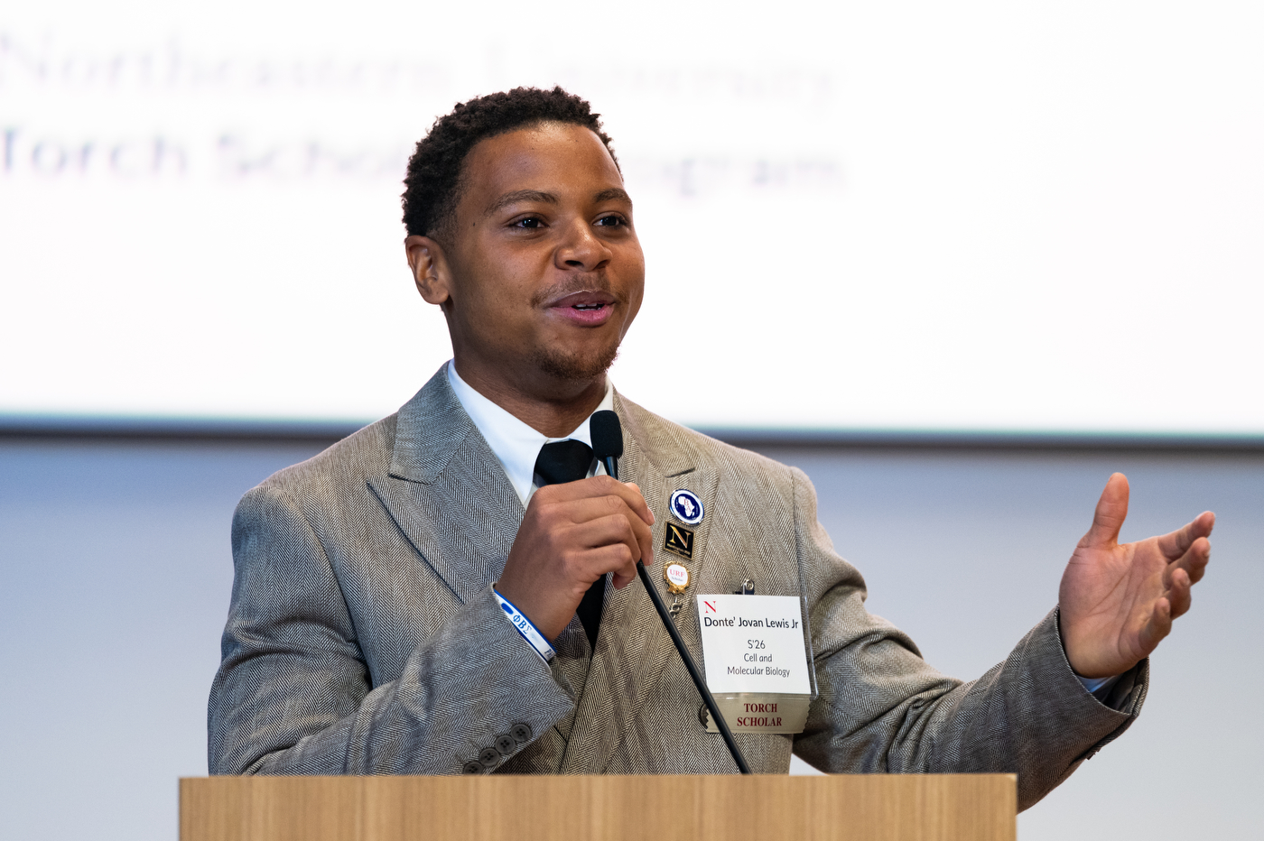 Donte Lewis speaking at a podium into a microphone at the Torch Scholars brunch.