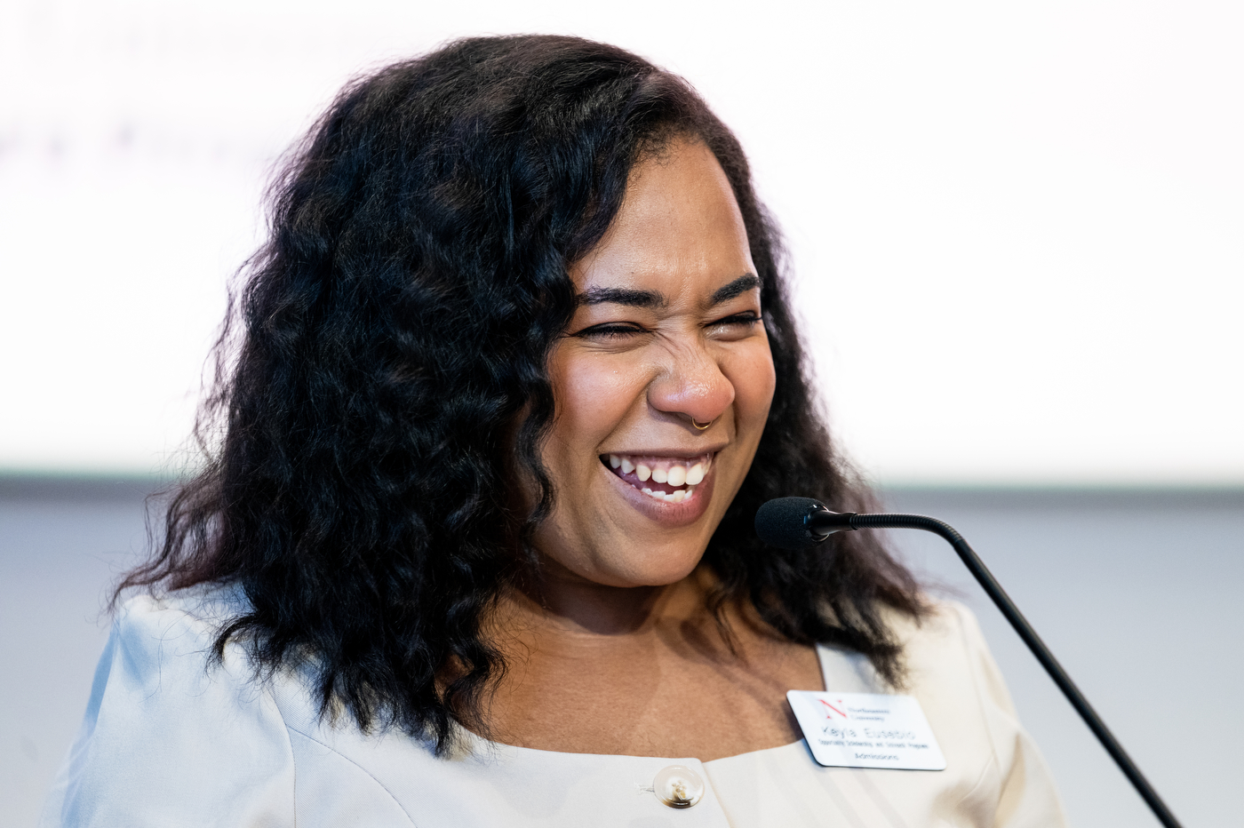 Keyla Eusebio smiling and tearing up while standing at a microphone in the Curry Ballroom.