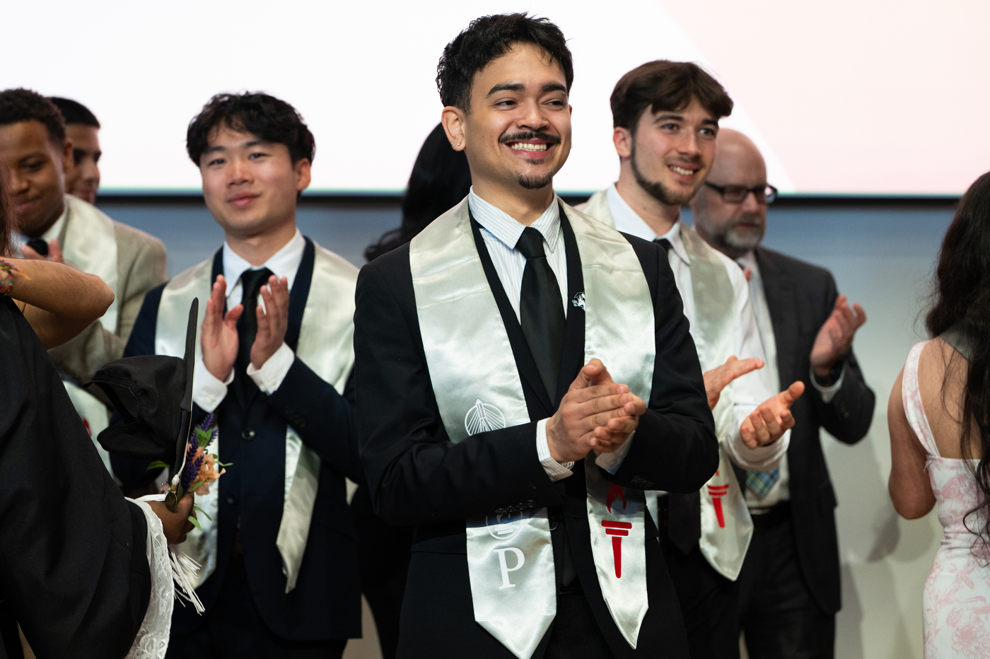 A group of Torch Scholars students standing on stage clapping.