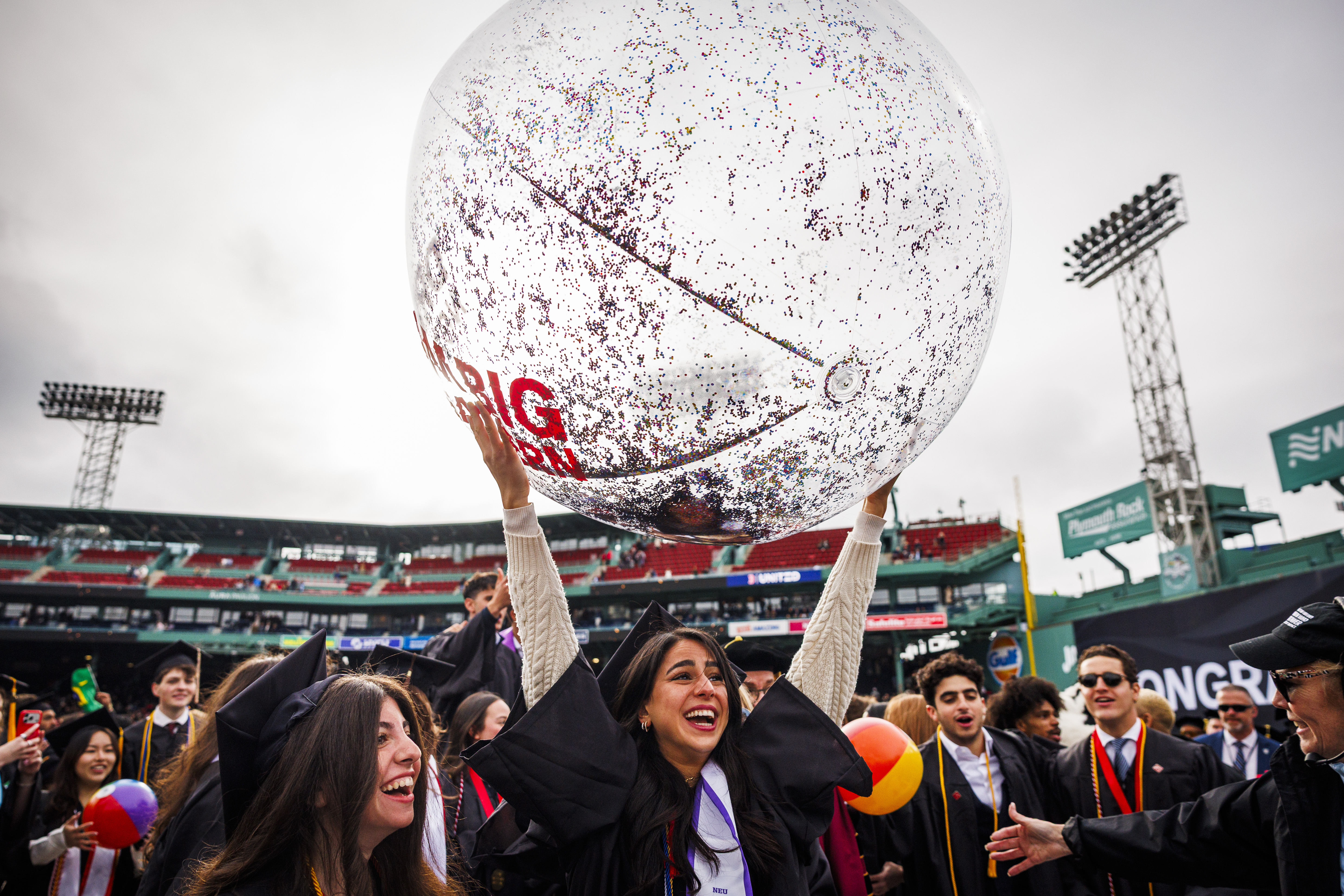 A graduate holds up an inflatable beach ball.
