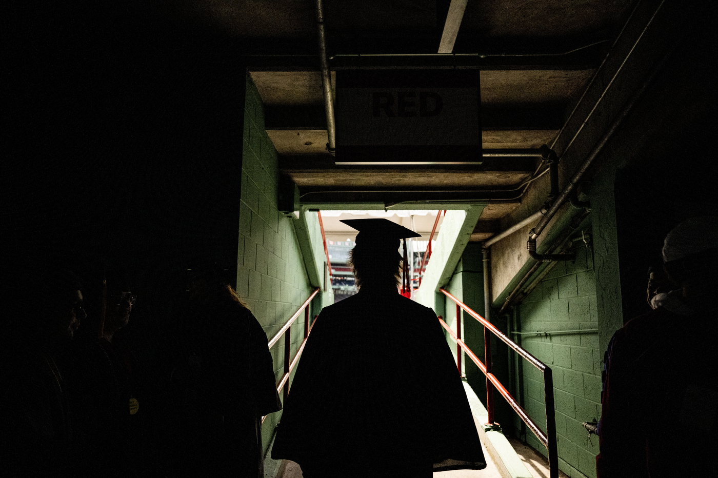 Behind the silhouette of a graduate walking through the tunnel at Fenway.
