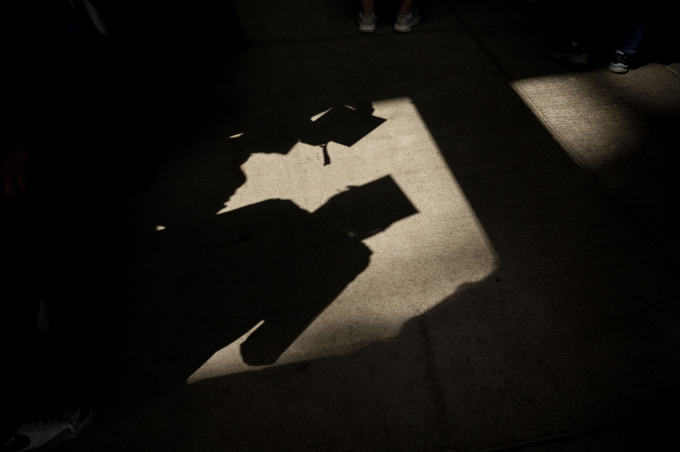 A dramatic close-up silhouette of a graduation cap and tassel against a dark background.