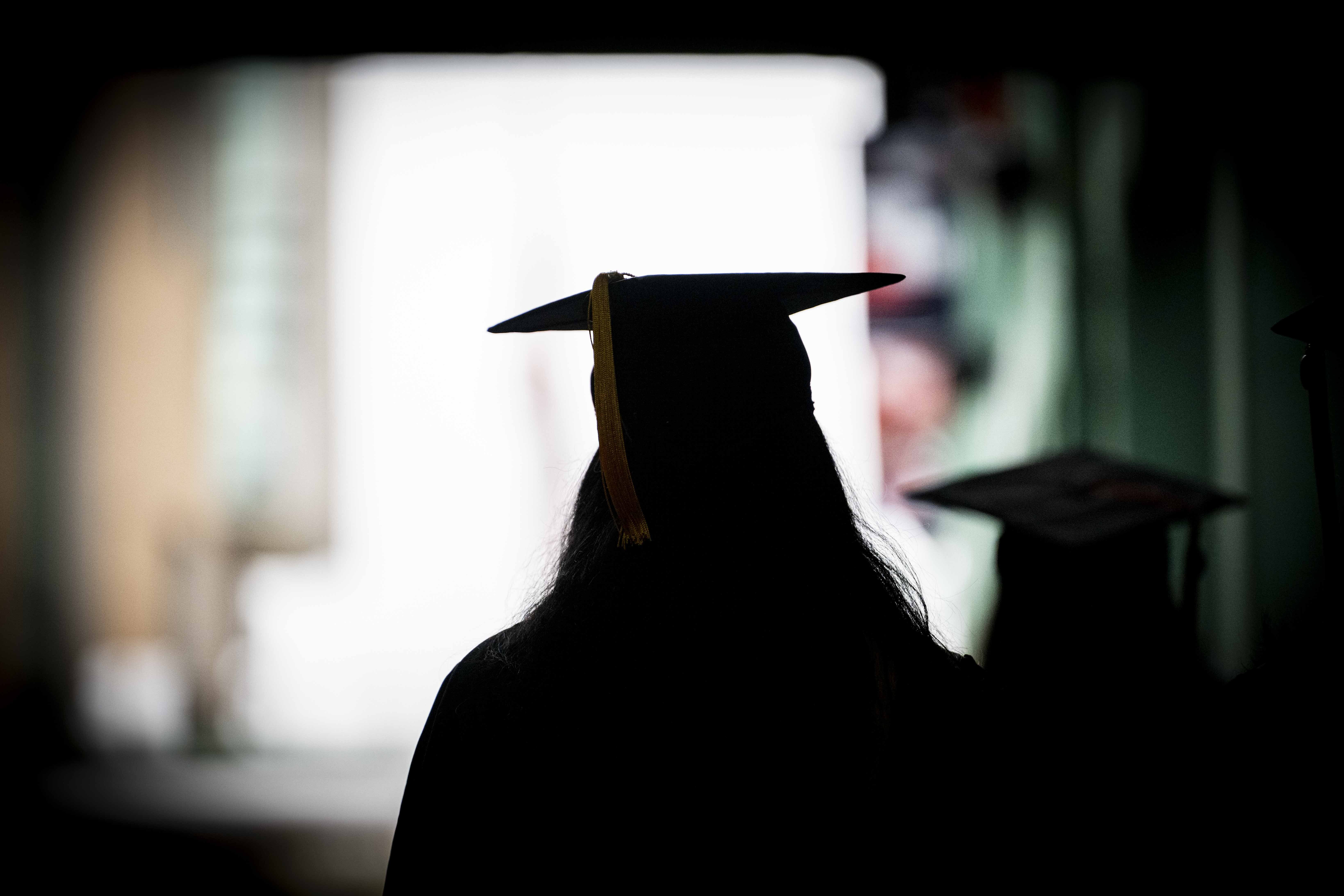 The silhouette of two students walking through a tunnel at Fenway Park. 